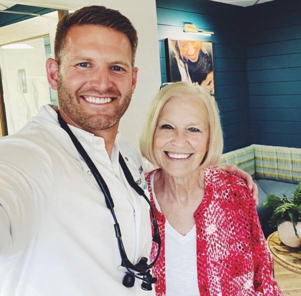 Dr Jordan Colby and his patient taking a photo with her dental implants in Oceanside